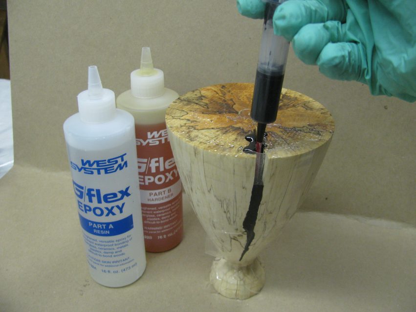 Cracks in the wooden goblet are filled by a syringe with a straw extension.